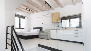 A modern bedroom with a bed, a gray sofa, and a wooden cabinet. - Rigas Boutique Rooms (Pefkochori)