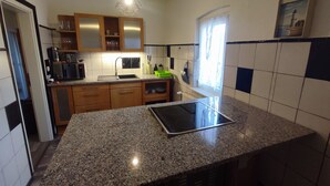 A kitchen with granite countertops, wooden cabinets, a built-in microwave, and a window with curtains. - 700 m from the beach, affordable and elegant. We are family and pet friendly (Heringsdorf)