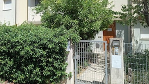 A residential building with a gated entrance, a small tree, and a hedge. - Cleo Limone (Falconara Marittima)