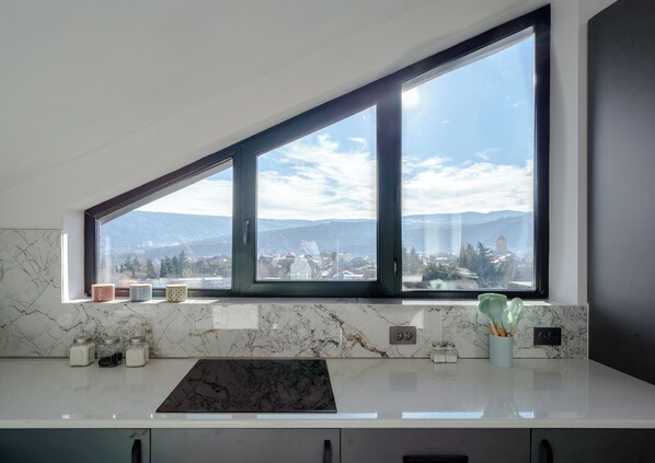 A kitchen with a large window overlooking a cityscape and mountains.