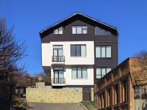 Un bâtiment à deux étages, doté d’un toit plat, de grandes fenêtres et d’un mur en pierre à l’avant.