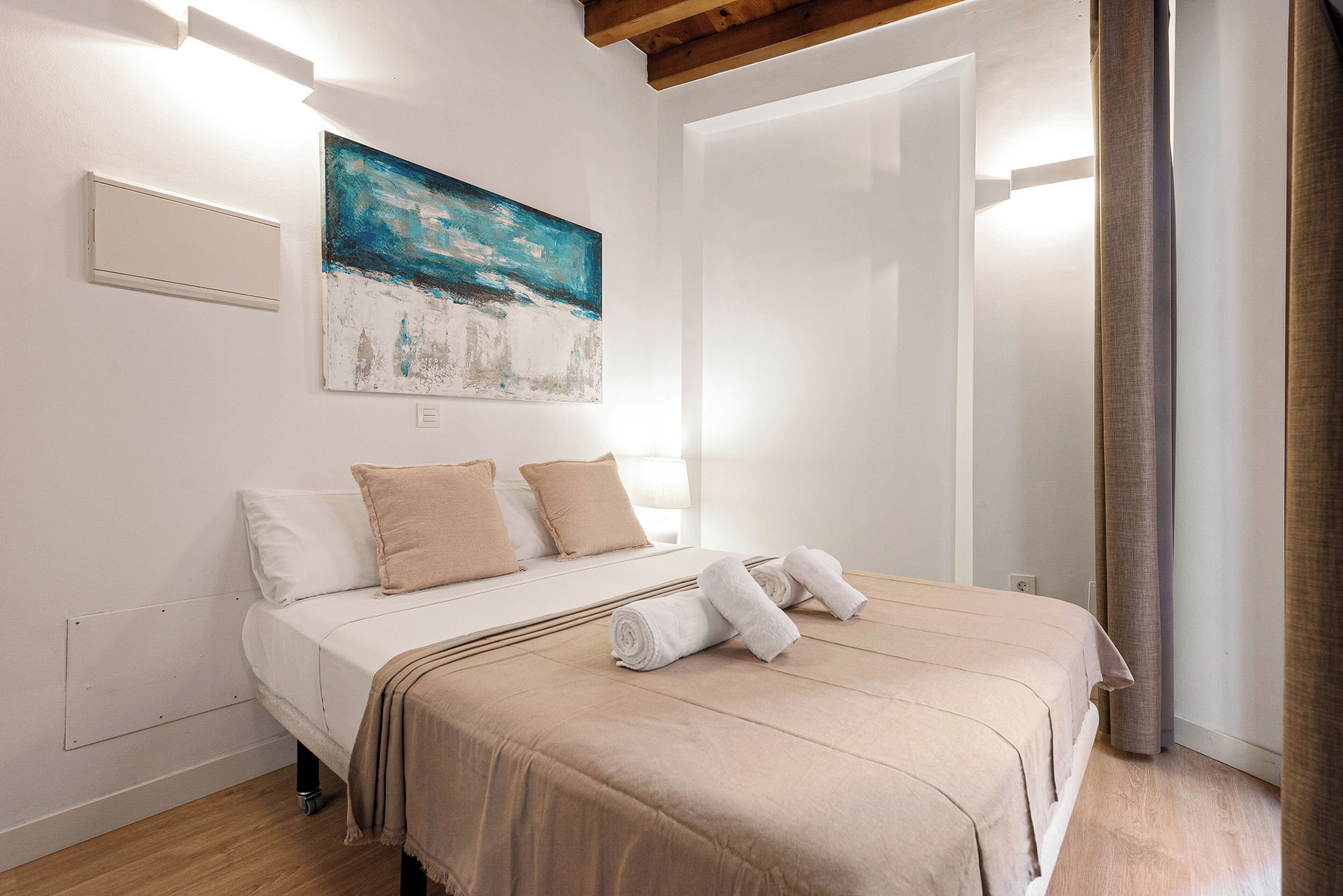 Ein Schlafzimmer mit Bett, Kissen, Decke und einem Bild an der Wand.
