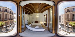 A modern hotel room with a large bed, a desk, and a view of the cityscape. - Stay U-nique Apartments Nosquera (Málaga)