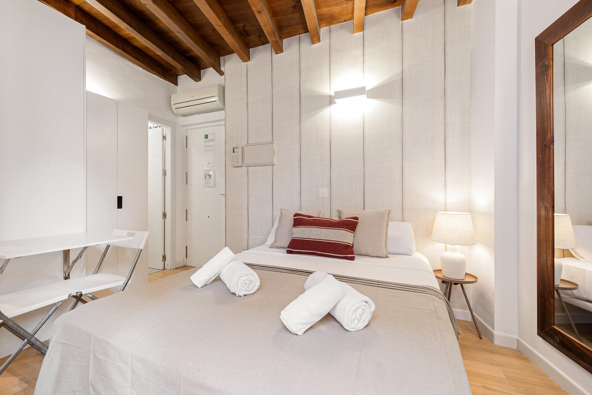 Een hotelkamer met een bed, nachtkastje, lamp en spiegel.