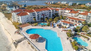 Un resort con varias edificaciones, una amplia piscina central y zona de playa.