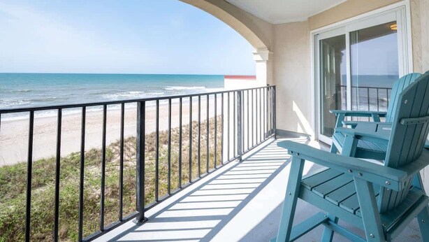 A balcony with a view of the beach and ocean.