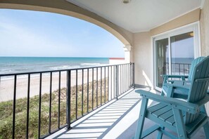 A balcony with a view of the beach and ocean.