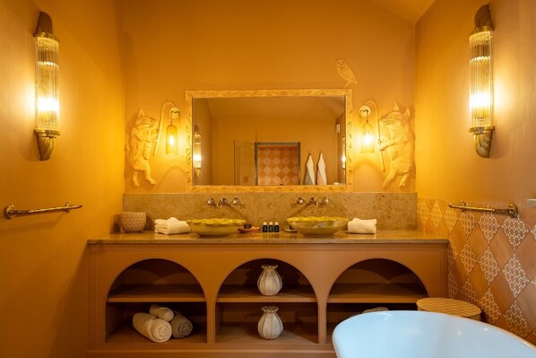 Une salle de bain avec un grand miroir, deux lavabos et une baignoire.