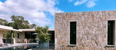 A modern house with a stone facade, a swimming pool, and a patio area.