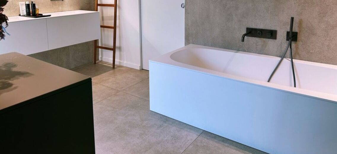 Een moderne badkamer met een vrijstaand bad, een houten trapje en een wit aanrecht.