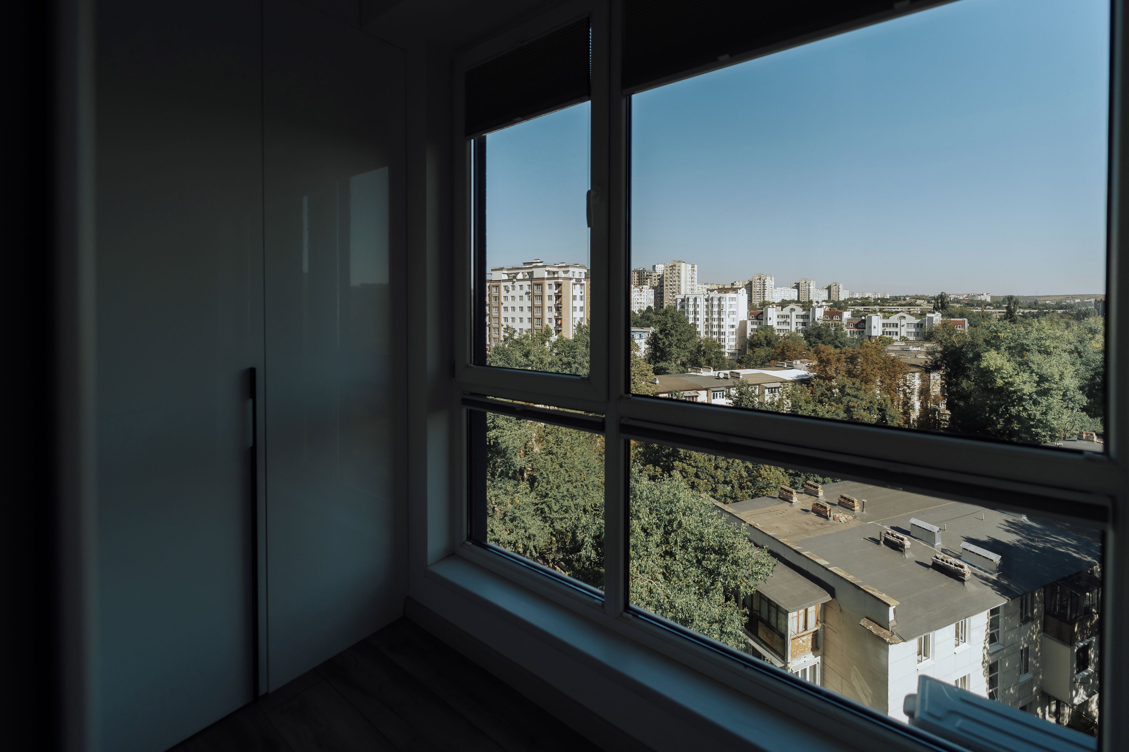 Una habitación con un amplio ventanal que da a un paisaje urbano con edificios y árboles.