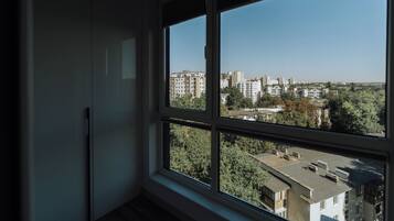 Una habitación con un amplio ventanal que da a un paisaje urbano con edificios y árboles.