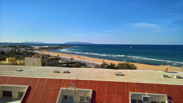 Vistes costaneres amb platja, oceà i muntanyes allunyades.