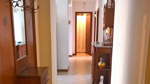 Un passadís amb un armari de fusta, una taula petita i una estant amb objectes decoratius.