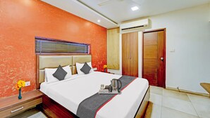 A hotel room with a bed, a ceiling fan, an air conditioning unit, and a wardrobe. - RG Suites Royapettah (Chennai)