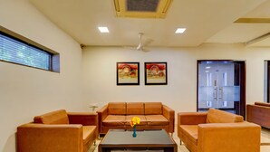 A modern living room with a brown leather sofa, a black coffee table, and two framed artworks on the wall. - RG Suites Royapettah (Chennai)