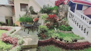 A garden with a table and chairs, a stone wall, and a staircase.