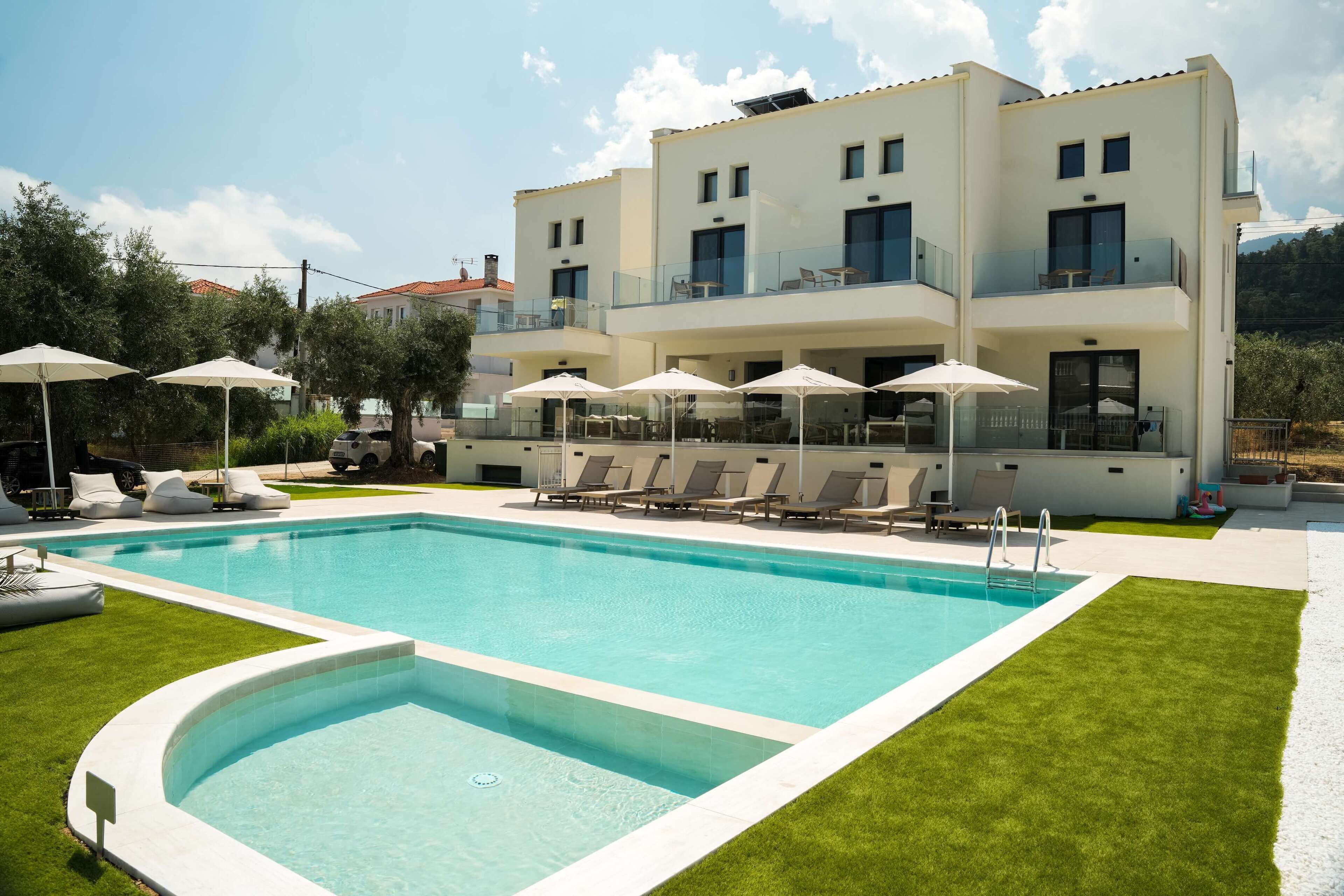 A modern building with a swimming pool, outdoor seating, and a well-maintained lawn.