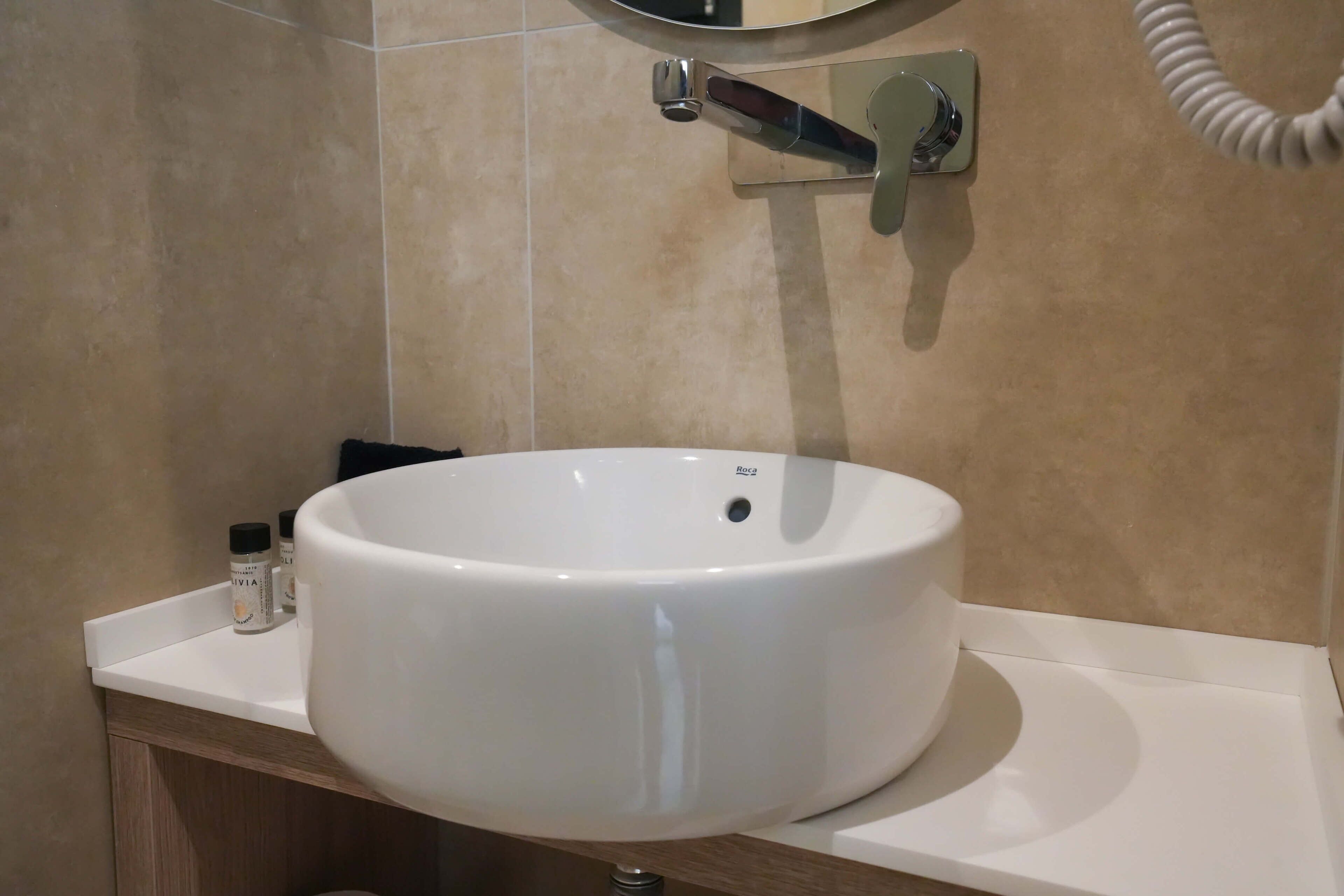 A bathroom with a white sink, a mirror, and a towel rack.