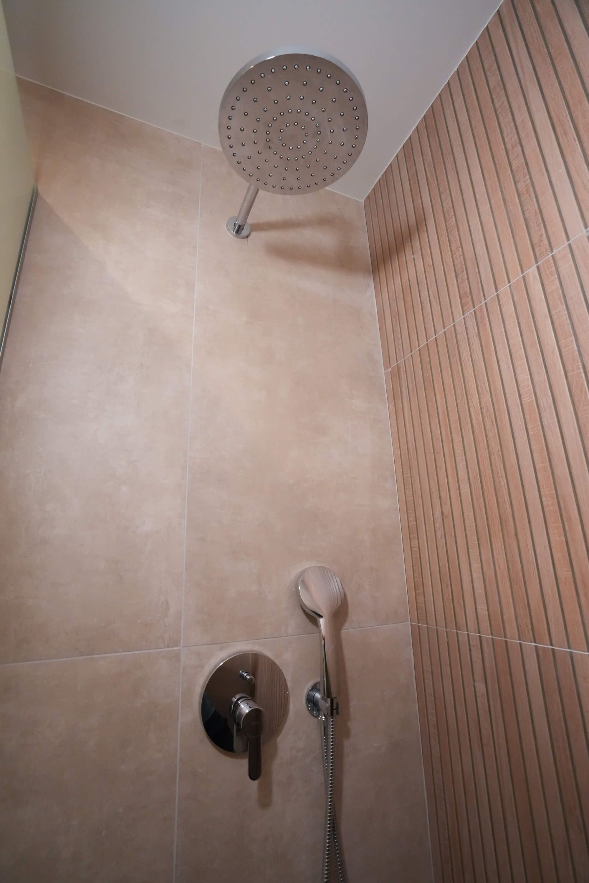 Un espace douche équipé d’un pommeau de douche à main et d’un robinet fixé au mur.