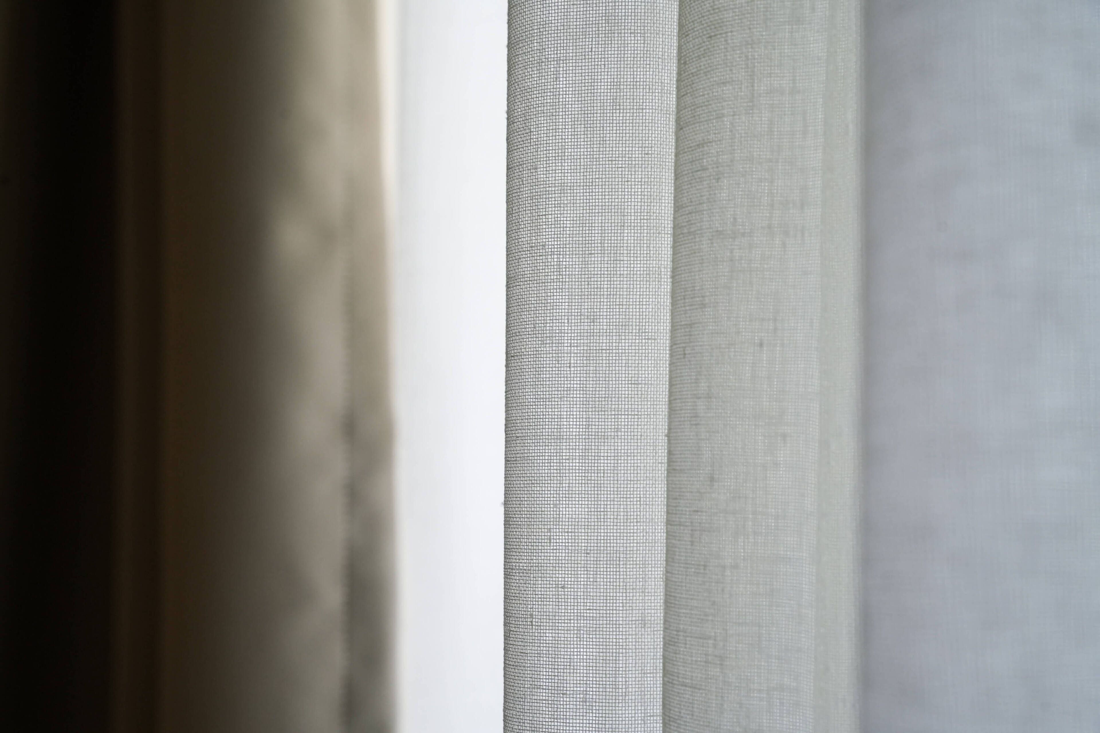 A close-up of a window with a textured blind partially drawn.