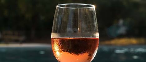 Una copa de vino rosado sobre un alféizar de piedra junto a una piscina.