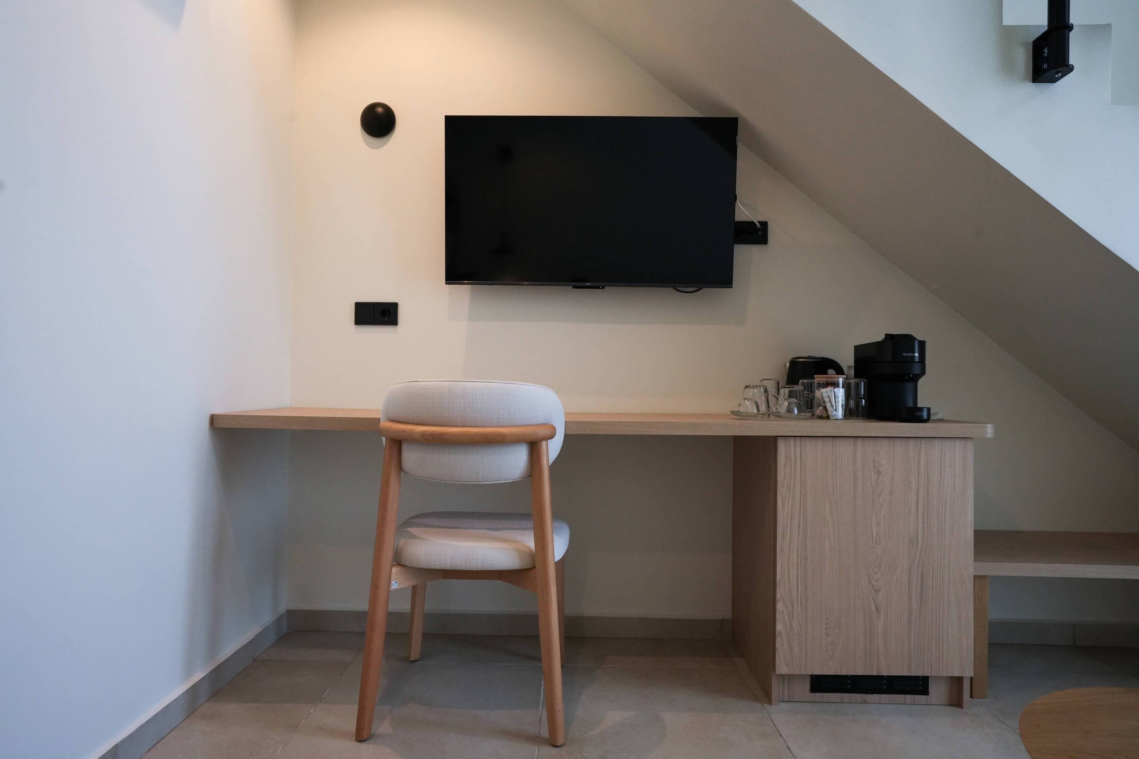 A modern kitchen with a wooden countertop, a built-in stove, and a flat-screen TV mounted on the wall.