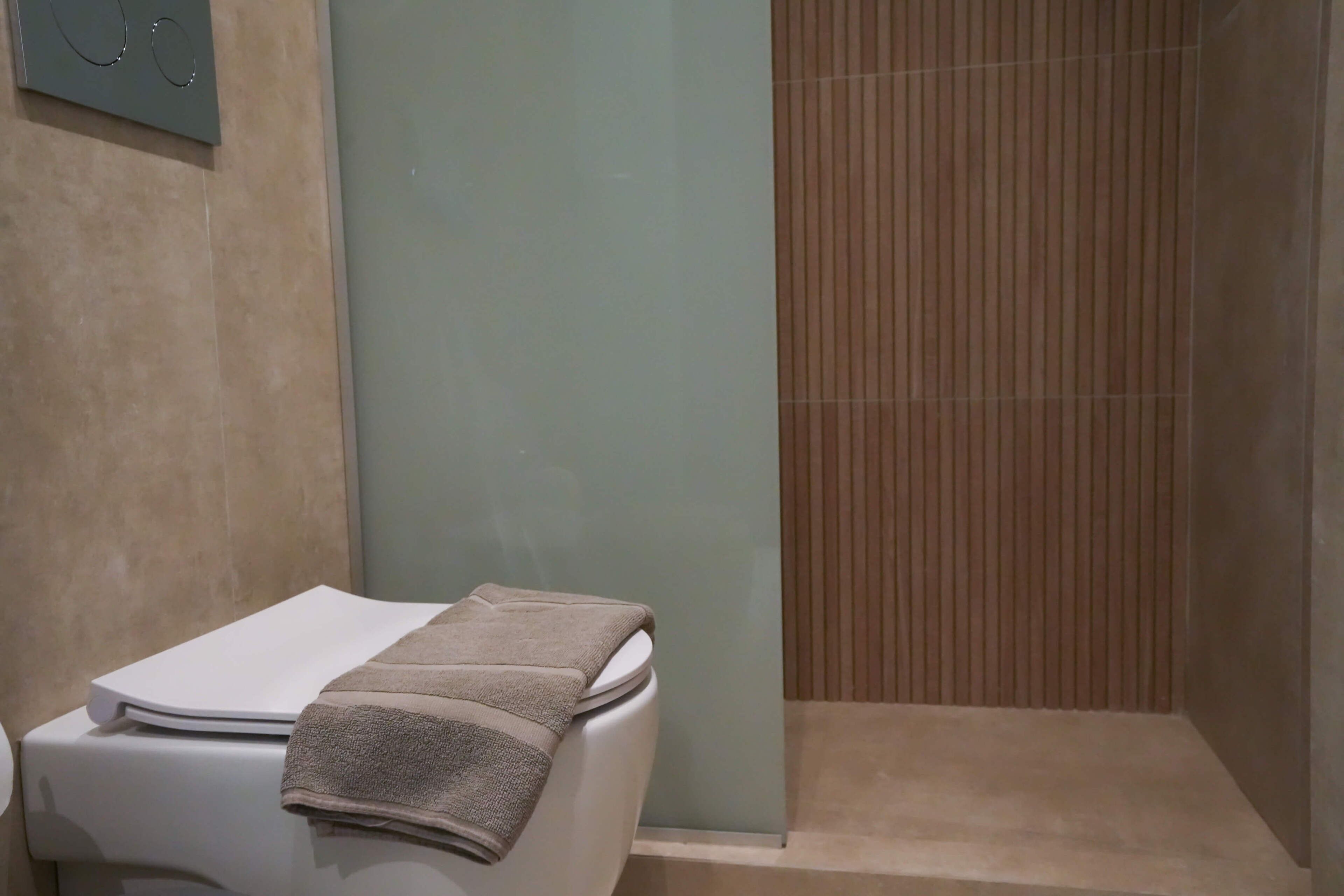 A bathroom with a toilet, a towel, and a shower area.