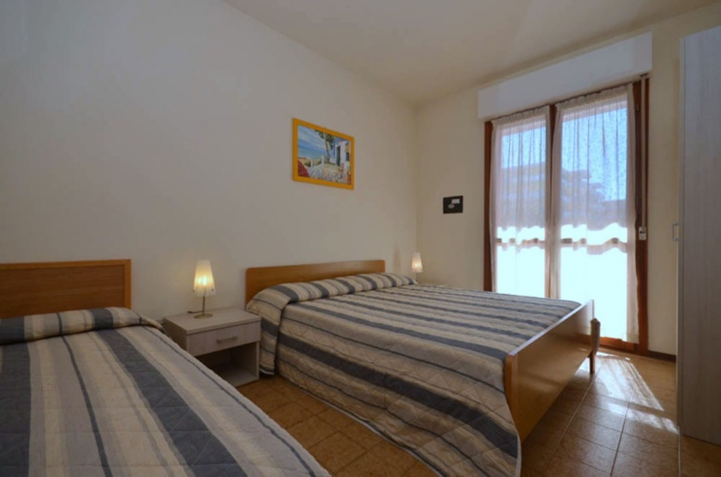 Un dormitorio con dos camas, una mesita de noche, una lámpara y un cuadro en la pared.