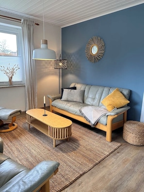Un salon moderne avec un canapé, une table basse, une lampe et un miroir décoratif.