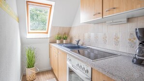 Une cuisine avec des meubles en bois, un four encastré, un évier et une fenêtre donnant sur un paysage verdoyant.