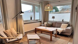 A living room with a sofa, a chair, a coffee table, and a lamp. - Ruhige Wohnung am Meer in SPO (Sankt Peter-Ording)