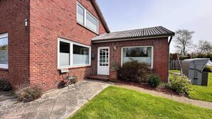 A two-story brick house with a small attached garage. - Ruhige Wohnung am Meer in SPO (Sankt Peter-Ording)