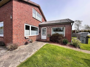 A two-story brick house with a front door, a small porch, and a well-maintained lawn. - Ruhige Wohnung am Meer in SPO (Sankt Peter-Ording)