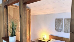 A bedroom with a wooden headboard, a bedside table with a lamp, a potted plant, and two wall-mounted decorative panels. - Ruhige Wohnung am Meer in SPO (Sankt Peter-Ording)