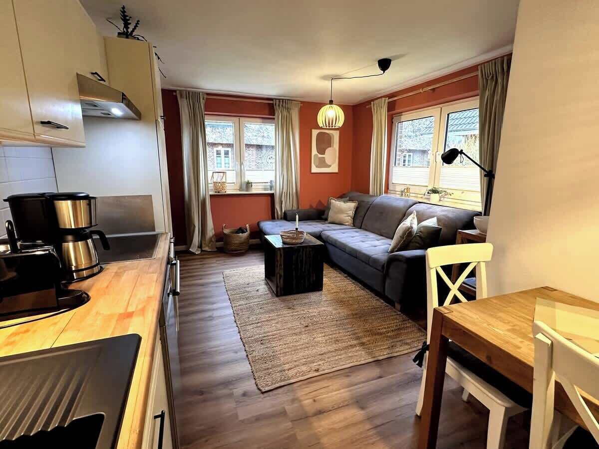 Un salon moderne comprenant un canapé, une table basse et une table à manger. Il y a également un coin cuisine avec une cuisinière et une machine à café.