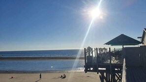 A beach with a wooden pier, a lifeguard tower, and a clear sky. - Strandhütte direkt am Leuchtturm und Strand in SPO (Sankt Peter-Ording)