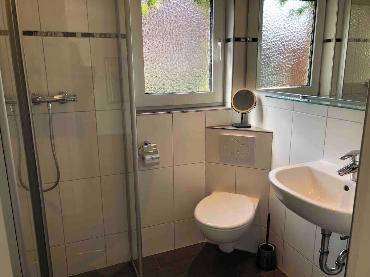 A small bathroom with a toilet, sink, and shower.