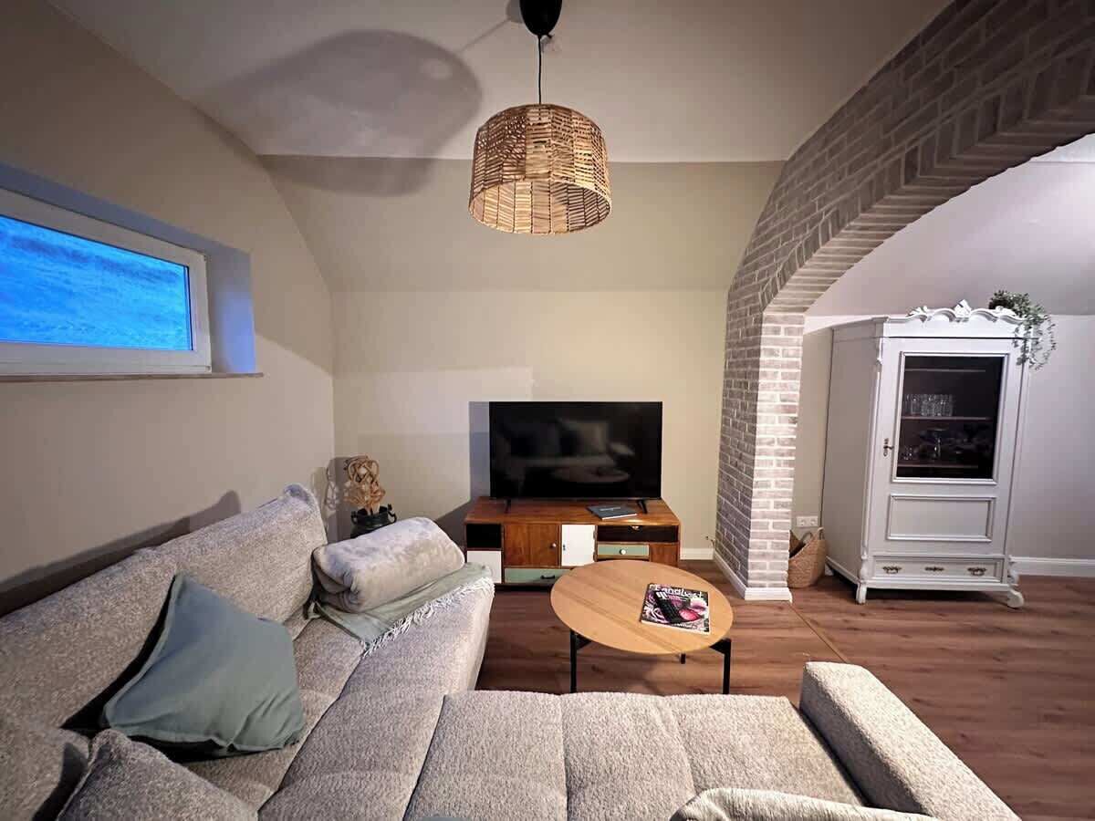 Un salon avec un canapé, une table basse, un téléviseur et un mur en briques.