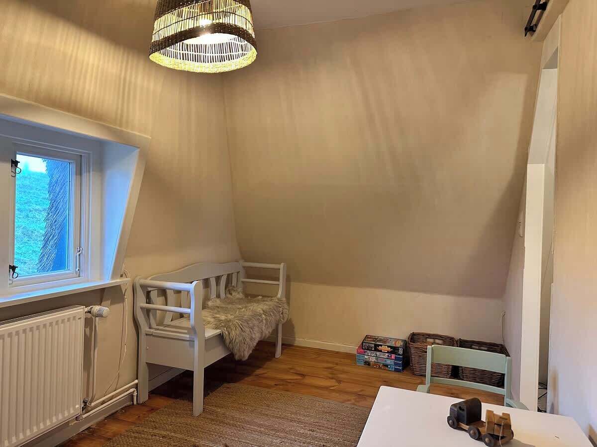 A child's bedroom with a bunk bed, a window, a radiator, and storage boxes.