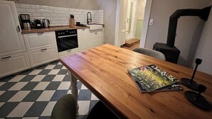 A compact kitchen with white cabinets, a wooden table, and a black stove.