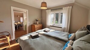 A bedroom with a bed, a dresser, a chair, and a window with curtains.