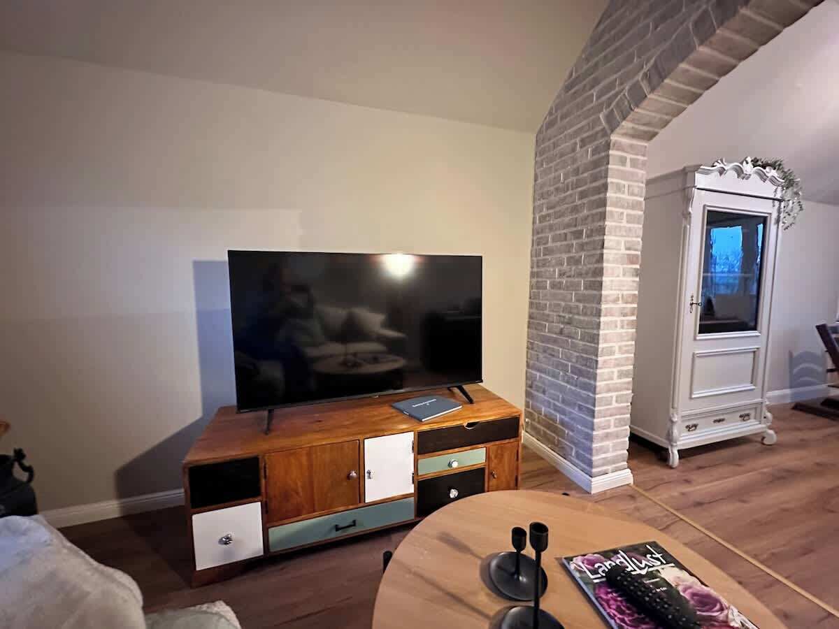 Un salon avec un téléviseur posé sur un meuble en bois, une cheminée et un meuble avec des tiroirs.
