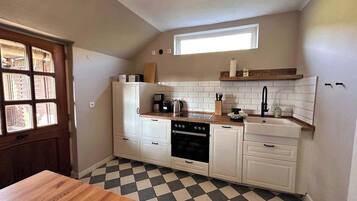 A compact kitchen with white cabinets, a black oven, a wooden countertop, and a checkered floor.