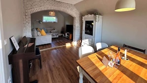A spacious living area with a brick fireplace, a dining table set for two, and a cozy seating area with a sofa and a coffee table.