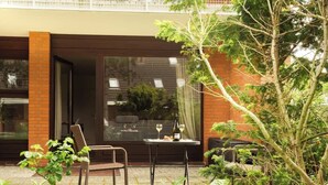 A modern outdoor seating area with a table, chairs, and a glass door leading to a room. - Zentrale Wohnung mit Terrasse & Boxspringbett (Sankt Peter-Ording)