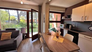 A modern kitchen with a dining area, large windows, and a view of the outdoors. - Zentrale Wohnung mit Terrasse & Boxspringbett (Sankt Peter-Ording)