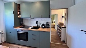 Cocina compacta con horno integrado, un lavamanos y cafetera.