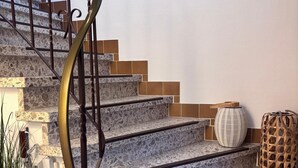 A staircase with a spiral metal railing, terrazzo steps, and a wall-mounted light fixture. - Quiet, comfortable apartment near the beach (Sankt Peter-Ording)