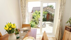 A dining area with a wooden table set for four, a vase of yellow flowers, and a bottle of wine. - 14 Shorwell (Southampton)
